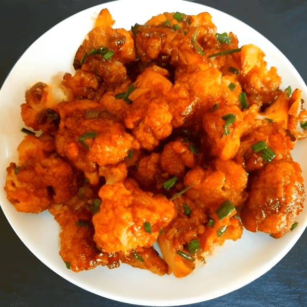Gobi Manchurian, a popular Indian appetizer, on a white plate with a dark background.