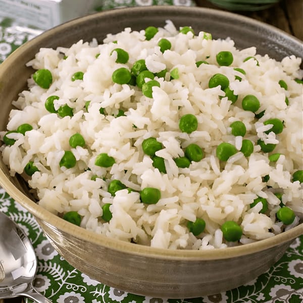 Close-up of a bowl of white rice mixed with bright green peas, a side dish from Tandoor Fine Indian Cuisine.