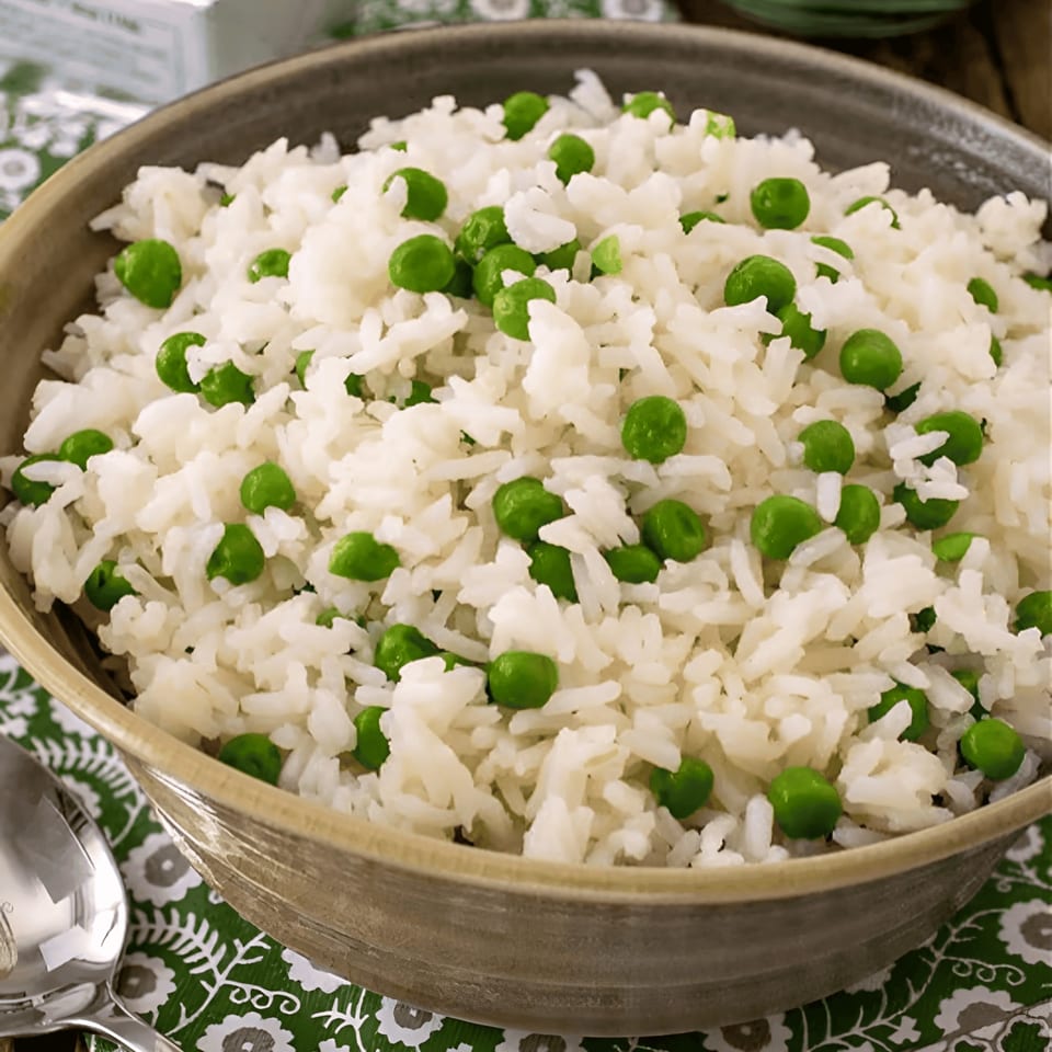Close-up of a bowl of white rice mixed with bright green peas, a side dish from Tandoor Fine Indian Cuisine.