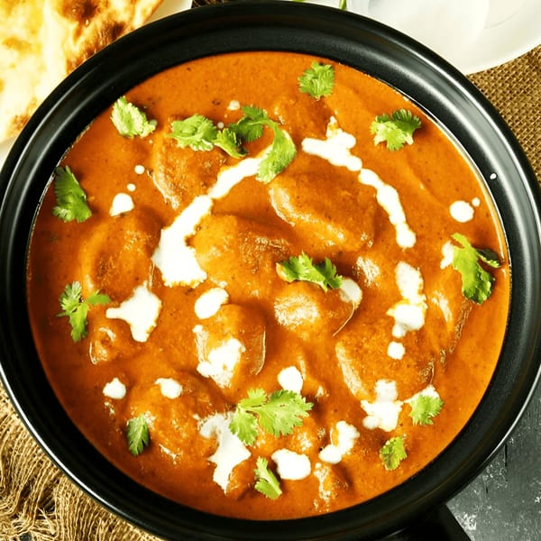 Tandoor Fine Indian Cuisine's butter chicken, garnished with cream and cilantro, served with naan.