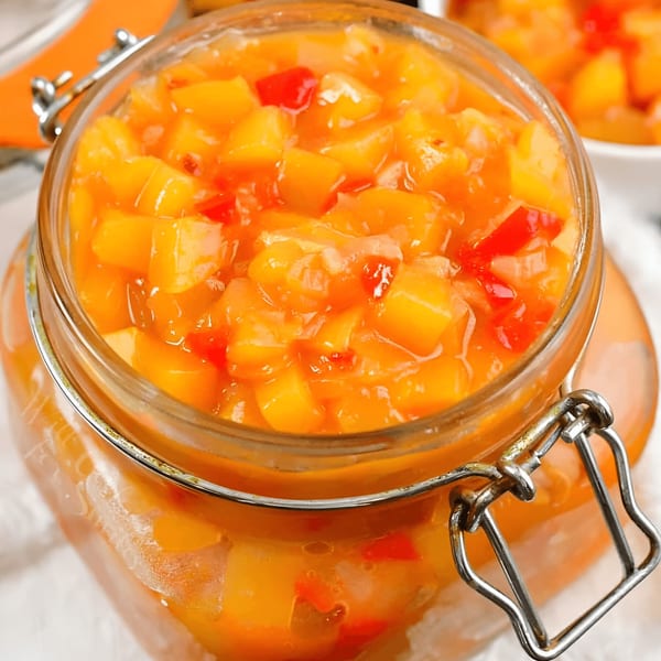Close-up of Tandoor Fine Indian Cuisine's vibrant mango chutney, with diced mango and red peppers in a glass jar.